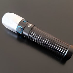 May include: A black flashlight with a textured grip and a white diffuser on the end. The flashlight has two blue buttons on the side.