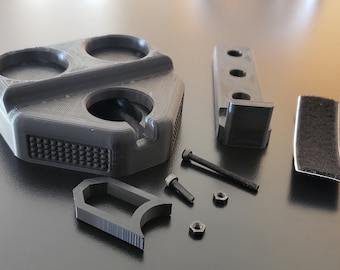 以下が含まれることがあります： 3Dプリントされた黒いオーガナイザー。円形のコンパートメントが3つ、フック、テクスチャ加工されたベースが付いています。オーガナイザーには、黒いプラスチック製の取り付けブラケット、黒いフック、黒い面ファスナーのストリップが付属しています。