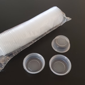 Puede incluir: Una bolsa de plástico transparente llena de una pila de pequeños vasos de plástico transparente. Se muestran tres vasos individuales fuera de la bolsa.