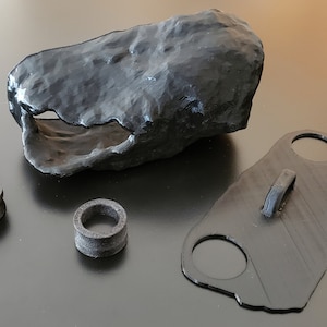 May include: A set of black 3D printed reptile habitat accessories, including a cave, a hide, and a water dish.