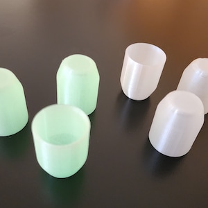 May include: Five 3D printed cups, three are light green and two are white. The cups are all the same size and shape.