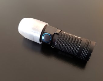 以下が含まれることがあります： 黒い懐中電灯に白いディフューザーが取り付けられています。懐中電灯はテクスチャ加工されたボディと青いボタンが付いています。