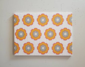 May include: A white background with a repeating pattern of orange, pink, and blue flowers. The flowers have a white center and are outlined in a darker orange.