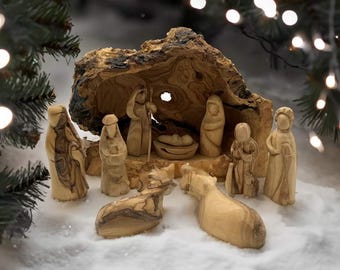 Può includere: Un presepe in legno in un presepe in legno d'ulivo intagliato. Le figure sono dipinte a mano e includono Maria, Giuseppe, Gesù bambino, un pastore e due animali.