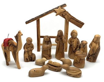 May include: A wooden nativity scene set with a camel, sheep, and figures of Mary, Joseph, and baby Jesus. The set is made of olive wood and has a natural wood finish.