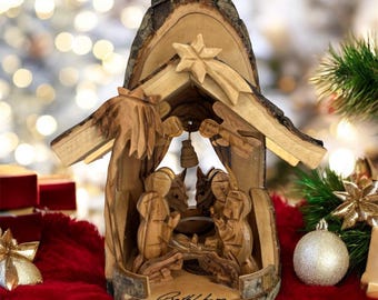 May include: A wooden nativity scene carved from olive wood. The scene depicts the baby Jesus, Mary, Joseph, and a star. The nativity scene is set in a small wooden stable with a thatched roof. The base of the nativity scene is inscribed with the word "Bethlehem".