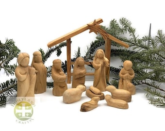 May include: A nativity scene set carved from olive wood. The set includes a stable, Mary, Joseph, baby Jesus, a shepherd, an angel, and three sheep. The figures are all hand-carved and painted in natural wood tones.