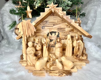 Può includere: Un presepe in legno con una stalla, una palma e figure di Maria, Giuseppe, Gesù bambino, pastori e animali. Le figure sono scolpite in legno d'ulivo e hanno una finitura in legno naturale.