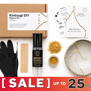 Op de afbeelding: Een Kintsugi DIY-reparatieset van Kinboru met een kartonnen doos, zwarte handschoenen, een penseel, houten roerstaafjes, epoxyhars, goudpoeder en diverse keramische kommen en scherven met goudkleurige barsten voor het herstellen van aardewerk.