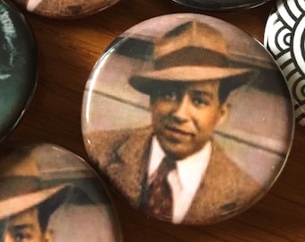 Puede incluir: Una colección de botones redondos con retratos vintage. Varios botones muestran a un hombre con traje y sombrero marrón, mientras que otros muestran a una mujer con un pañuelo rojo. Los botones tienen un acabado brillante.
