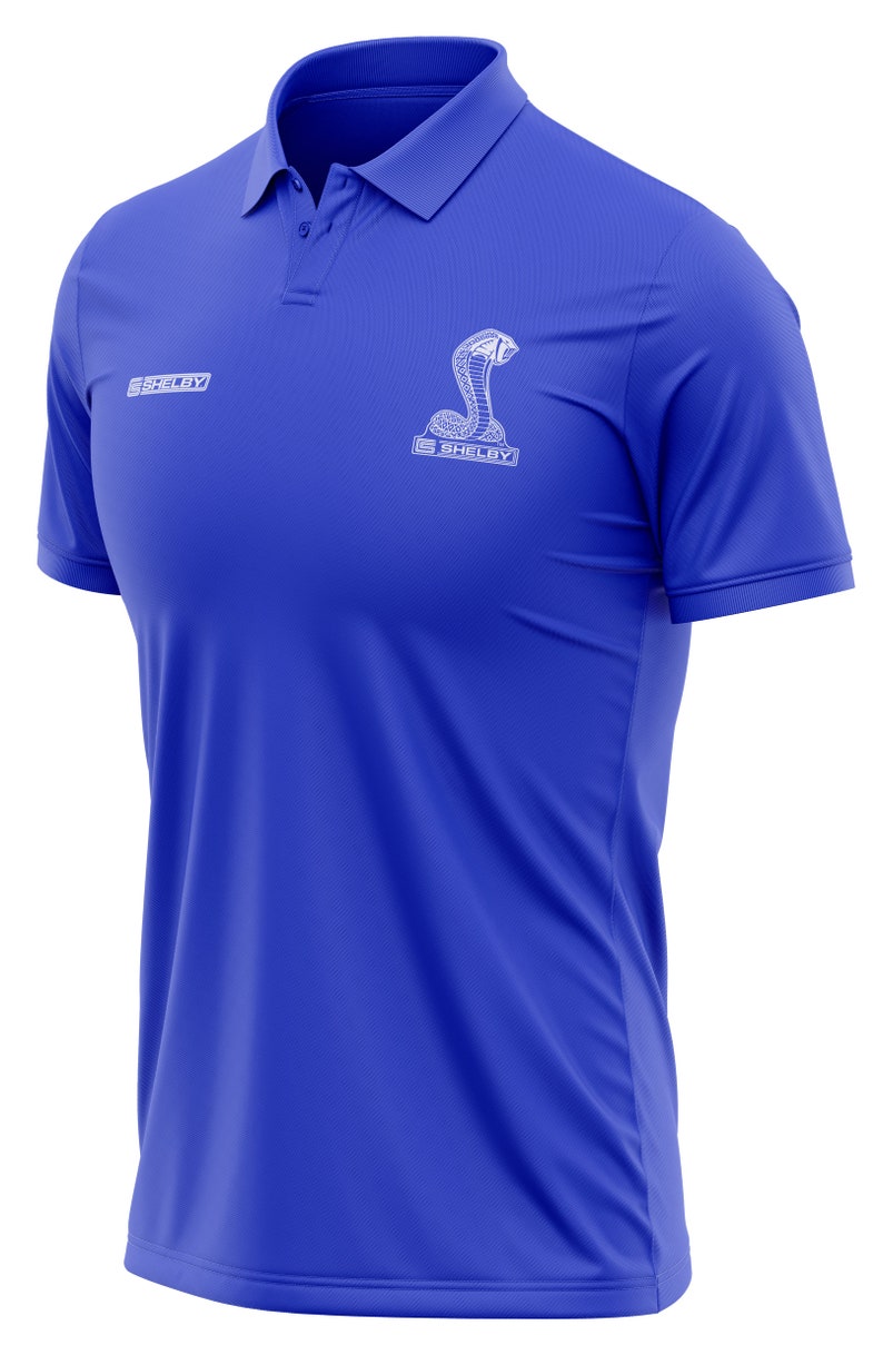 Puede incluir: Una camiseta polo azul real con un logotipo bordado blanco de Shelby Cobra en el pecho.