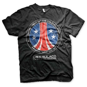 Pode incluir: Camiseta preta com um gráfico circular desbotado do logotipo do U.S.S. Sulaco do filme Aliens. O logotipo apresenta um design vermelho, branco e azul com estrelas e o texto "Department of the Colonial Navy" e "U.S. Colonial Marines". O texto "U.S.S. Sulaco" está impresso abaixo do logotipo.