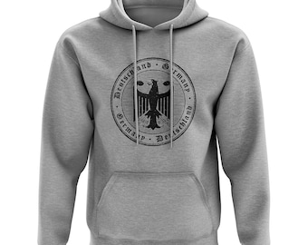 Könnte beinhalten: Ein grauer Kapuzenpullover mit einer schwarzen und weißen kreisförmigen Grafik des deutschen Adlers mit dem Text "Deutschland and Germany" um den Adler.