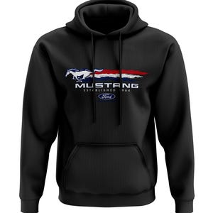 Könnte beinhalten: Schwarzer Kapuzenpullover mit einem weißen Ford Mustang-Logo und dem Text "Mustang Established 1964" in Weiß. Das Logo zeigt ein weißes Pferd, das mit einem rot-weiß-blauen Streifen dahinter rennt.