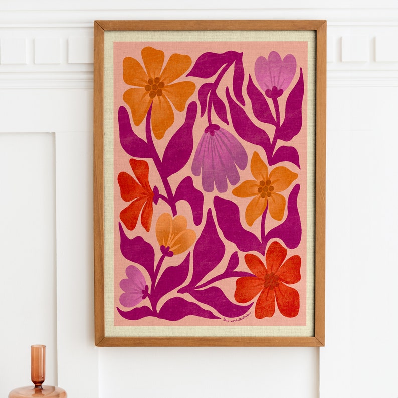 May include: A framed print with a floral design featuring pink, orange, and red flowers on a light pink background. The print has a pink and white floral pattern with a pink background. The print is framed in a natural wood frame.
