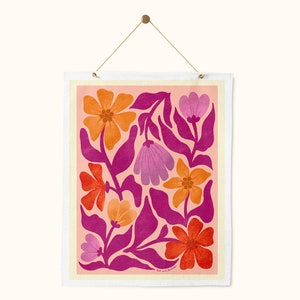 May include: A pink and orange floral print wall hanging with a white border. The flowers are stylized and have a retro feel.