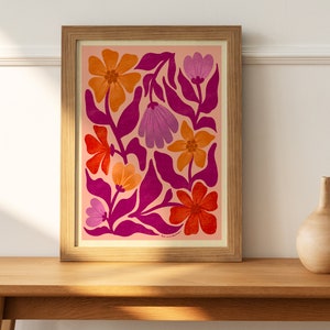May include: A framed print with a pink background and a floral pattern in shades of orange, red, and purple. The flowers are stylized and have a retro feel.