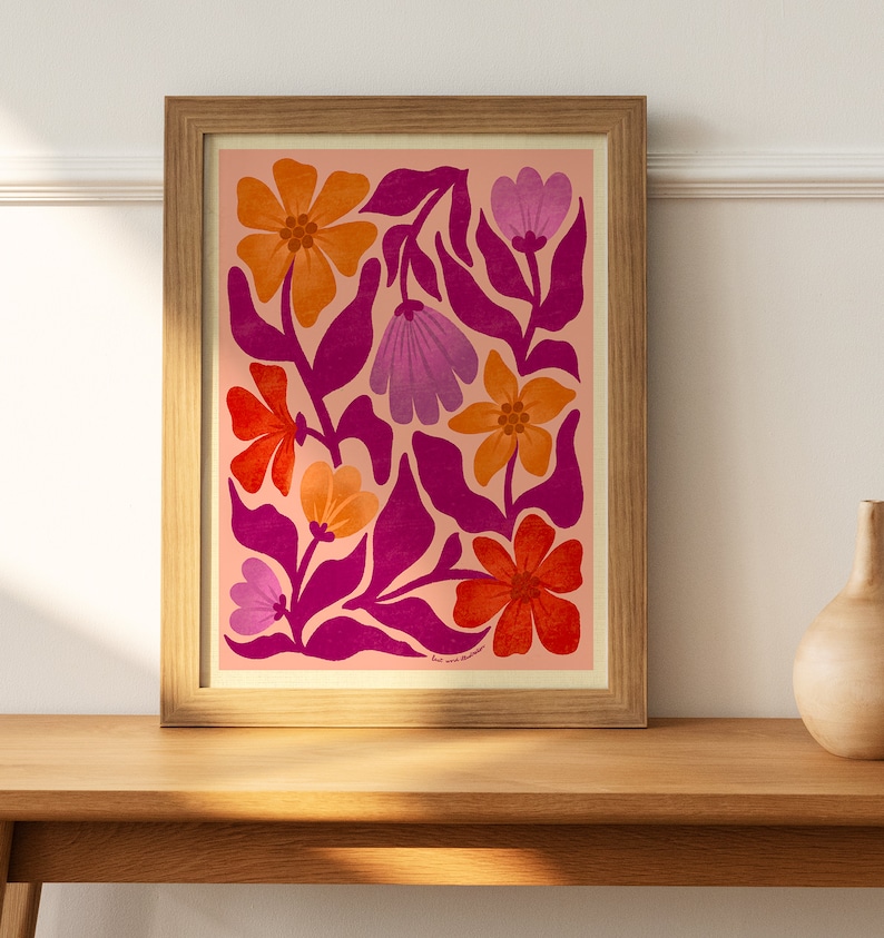 May include: A framed print with a pink background and a floral pattern in shades of orange, red, and purple. The flowers are stylized and have a retro feel.
