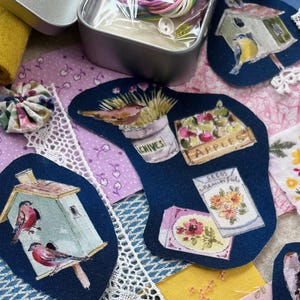 May include: A collection of fabric scraps featuring birds, flowers, and gardening-themed designs. The scraps are arranged on a light brown surface with a variety of colors, including blue, green, yellow, pink, and white. The scraps are perfect for crafting projects like quilting, applique, and embroidery.