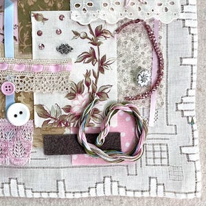 May include: A fabric collage featuring various textures and patterns. It includes floral prints, lace, ribbons, buttons, and embroidery floss in shades of pink, white, and green. The collage is set on a white, patterned background.