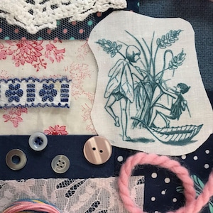May include: A white fabric patch with a blue embroidered design of two fairies standing in a field of tall grass. The fairies are wearing simple dresses and have wings. The grass is tall and green, and there are small flowers scattered throughout the field.