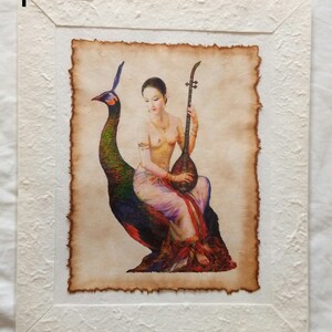May include: A framed painting of a woman sitting on a peacock, playing a stringed instrument. The woman is wearing a white and red dress and has long dark hair. The peacock is green and blue with a long tail. The painting is on a parchment-like background.