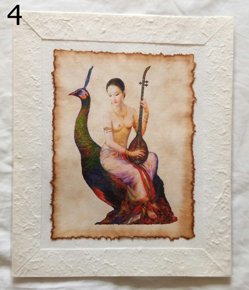 May include: A framed painting of a woman sitting on a peacock, playing a stringed instrument. The woman is wearing a white and red dress and has long dark hair. The peacock is green and blue with a long tail. The painting is on a parchment-like background.