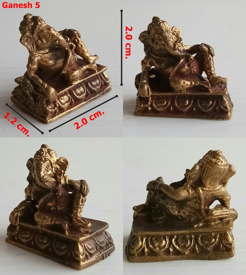 Może przedstawiać: Mała, brązowa statua Ganeshy o wymiarach 2,0 cm długości, 1,2 cm szerokości i 2,0 cm wysokości. B&oacute;stwo przedstawione jest w pozycji leżącej na ozdobnej podstawie. Posąg ma skomplikowane detale i czerwonobrązowy odcień.