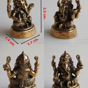 Może przedstawiać: Mała, brązowa statua Ganeshy, o wysokości około 2,3 cm, szerokości 1,7 cm i głębokości 1,4 cm. Statua przedstawia hinduskie b&oacute;stwo Ganeszę z wieloma ramionami i głową słonia. Podstawa to prostokąt o zaokrąglonych krawędziach. Obraz jest oznaczony jako "Ganesh 4".