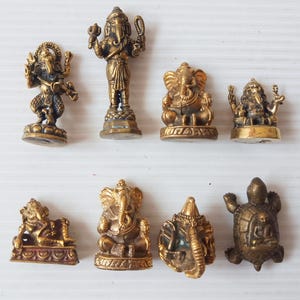 A collection of various small brass Ganesha amulets in different poses and one brass turtle amulet, handcrafted divine remover of obstacles for success and prosperity. Price per one piece.