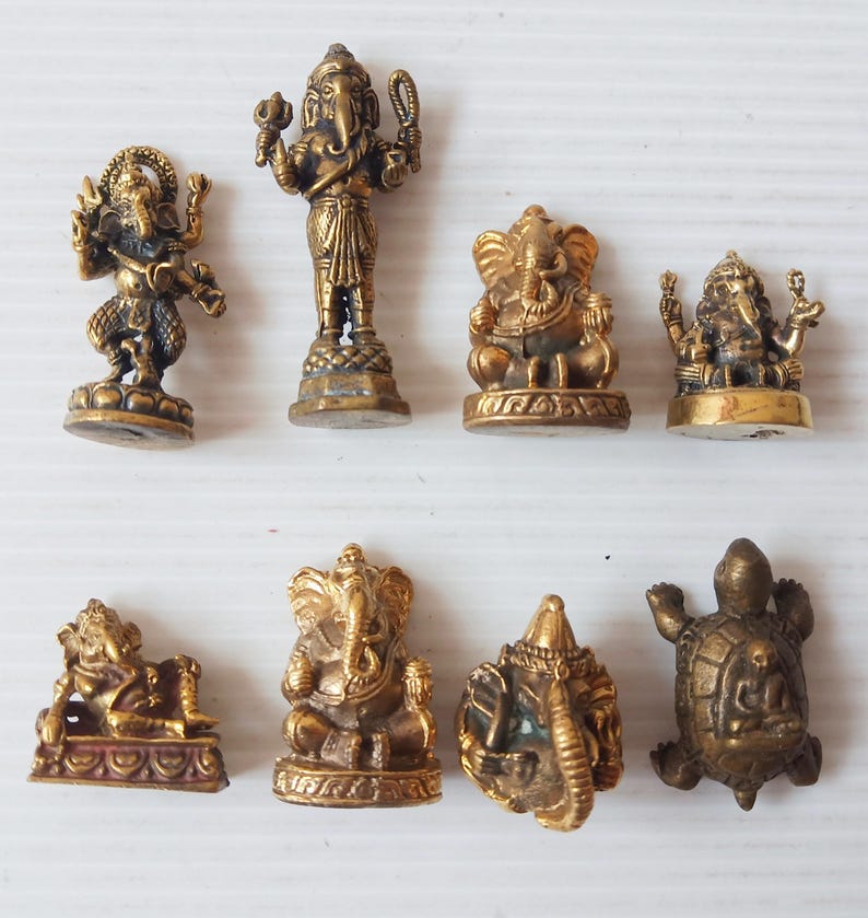 A collection of various small brass Ganesha amulets in different poses and one brass turtle amulet, handcrafted divine remover of obstacles for success and prosperity. Price per one piece.