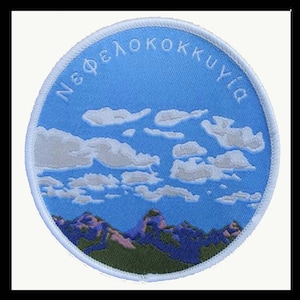 May include: A white circular patch with a blue sky and white clouds. The text "Νεφελοκοκκυγία" is written in white around the edge of the patch.