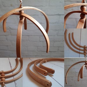 Può includere: Un mobile per bambini in legno con tre cerchi e perline di legno. Il mobile è sospeso da un gancio di metallo.