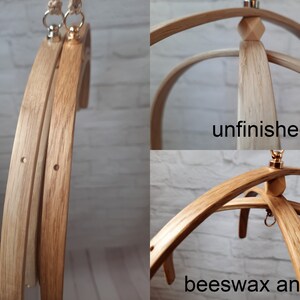 May include: Two wooden baby mobile frames, one unfinished and one finished with beeswax and oil. Both frames have a gold metal hook and a wooden knob at the top.