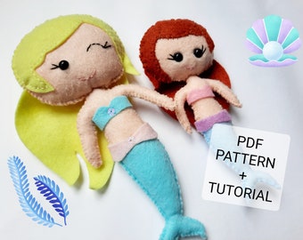 May include: Two felt mermaid dolls with long hair, one with yellow hair and one with red hair. The dolls are wearing blue and pink felt mermaid tails and have embroidered faces. The image also includes a felt seashell and a sign that says "PDF PATTERN + TUTORIAL".