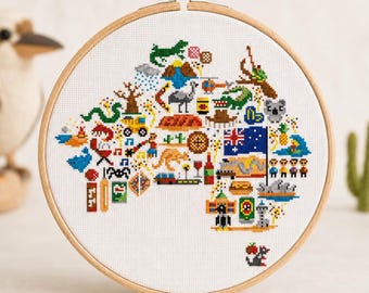 Peut inclure: Un tambour à broder en bois circulaire contenant un motif au point de croix représentant le continent australien. Le design présente des icônes pixelisées colorées illustrant divers animaux, monuments et symboles culturels sur la carte.