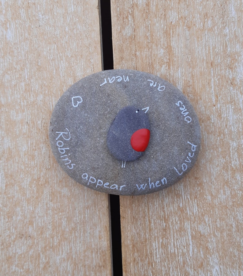 May include: A gray stone painted with a robin and the words "Robins appear when loved ones are near".