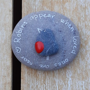 May include: A gray stone painted with a robin and the words "Robins appear when loved ones are near".