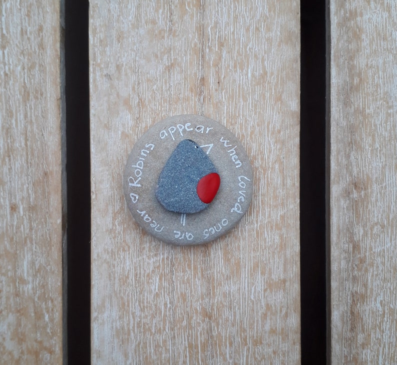 May include: A round stone with a painted robin and the text "Robins appear when loved ones are near".