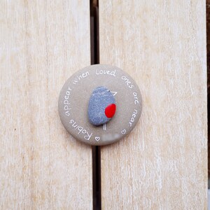 May include: A round stone with the words "Robins appear when loved ones are near" written on it. A small painted robin is in the center of the stone.