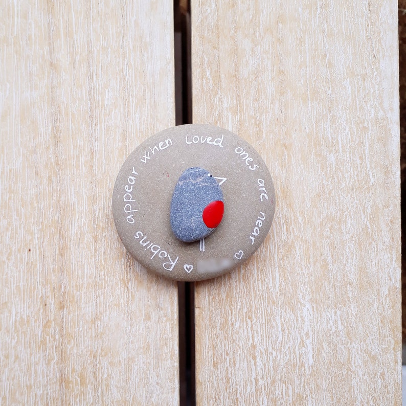 May include: A round stone with the words "Robins appear when loved ones are near" written on it. A small painted robin is in the center of the stone.
