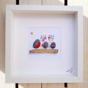 May include: Framed pebble art depicting three robins perched on a branch with colorful flowers behind them. The artwork is signed "Aaschw Art 2018".