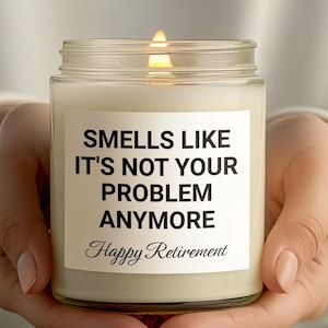 以下が含まれることがあります： 黒いラベルに「もうあなたの問題じゃないみたい。ハッピーリタイアメント」と書かれた白いキャンドルです。
