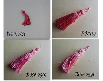 May include: Four decorative tassels in various shades of pink and red. The tassels are labeled "Vieux rose", "Pêche", "Rose 2591", and "Rose 2590". Each tassel has a beaded top and a fringe of silky threads.