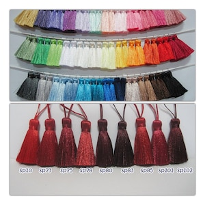 May include: A close-up of ten red tassels with gold accents. The tassels are arranged in a row and labeled with the product codes SP10, SP73, SP75, SP78, SP80, SP83, SP85, SP101, and SP102.