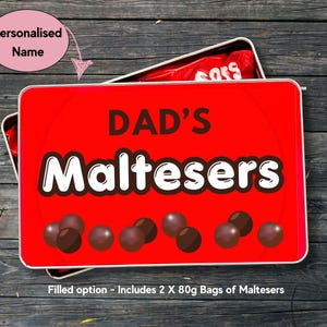 May include: A rectangular red metal tin with a lid featuring the text DAD'S Maltesers in black and white lettering, decorated with illustrations of brown chocolate balls. The tin contains two 80g bags of Maltesers chocolate candy.