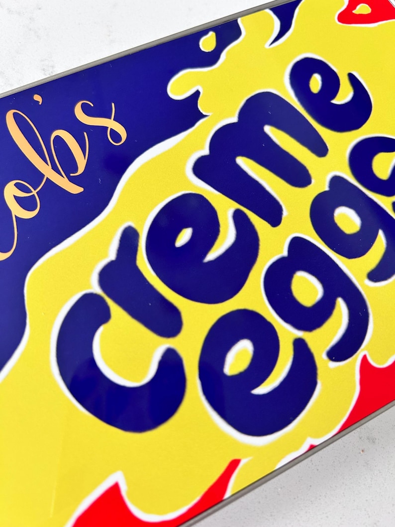 May include: A close-up of a yellow and blue box with the words "Creme Eggs" in a white outline. The box has a red and white border.