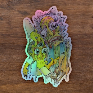 Pode incluir: Um adesivo holográfico com uma ilustração de desenho animado de dois personagens com múltiplos olhos e baba pingando. Os personagens estão em um esquema de cores verde, azul e amarelo.