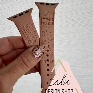 May include: A pink silicone watch band with a custom design featuring the text "Taylor's Version", "Karma is the guy on the Chiefs", "13", "87", and "Loyer". The band also features a football, musical notes, and stars.
