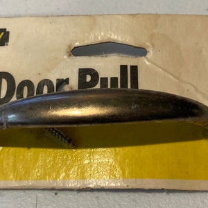 May include: A Stanley 4-7/8" door pull, brass finish, on a yellow and white card. The door pull is a curved handle with screw attachments. The packaging includes the Stanley logo and product information.